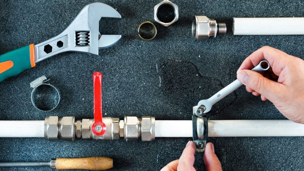 Plumber repairing a pipe valve with an adjustable wrench in North Miami Beach