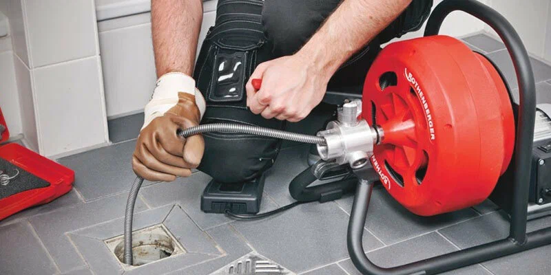 Plumber using a drain-cleaning machine in North Miami Beach