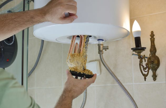 Technician removing mineral buildup from a water heater in North Miami Beach